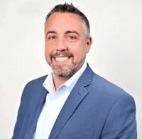 Professional businessman in a blue suit smiling, representing the Apopka Area Chamber of Commerce’s community and business networking efforts.